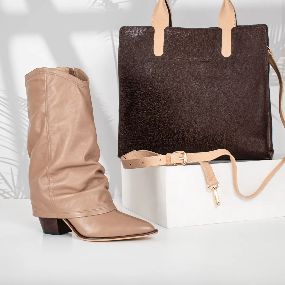 A nude folded-shaft leather boot beside a dark leather bag