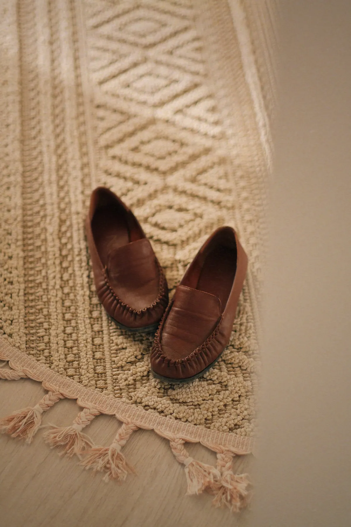 A pair of chestnut loafers resting on a woven rug
