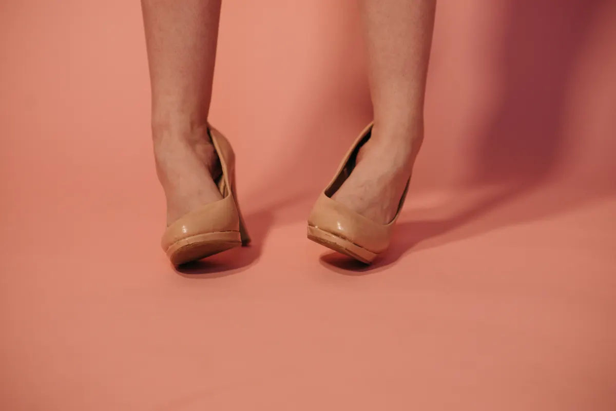 Feet in nude pumps standing on a coral floor